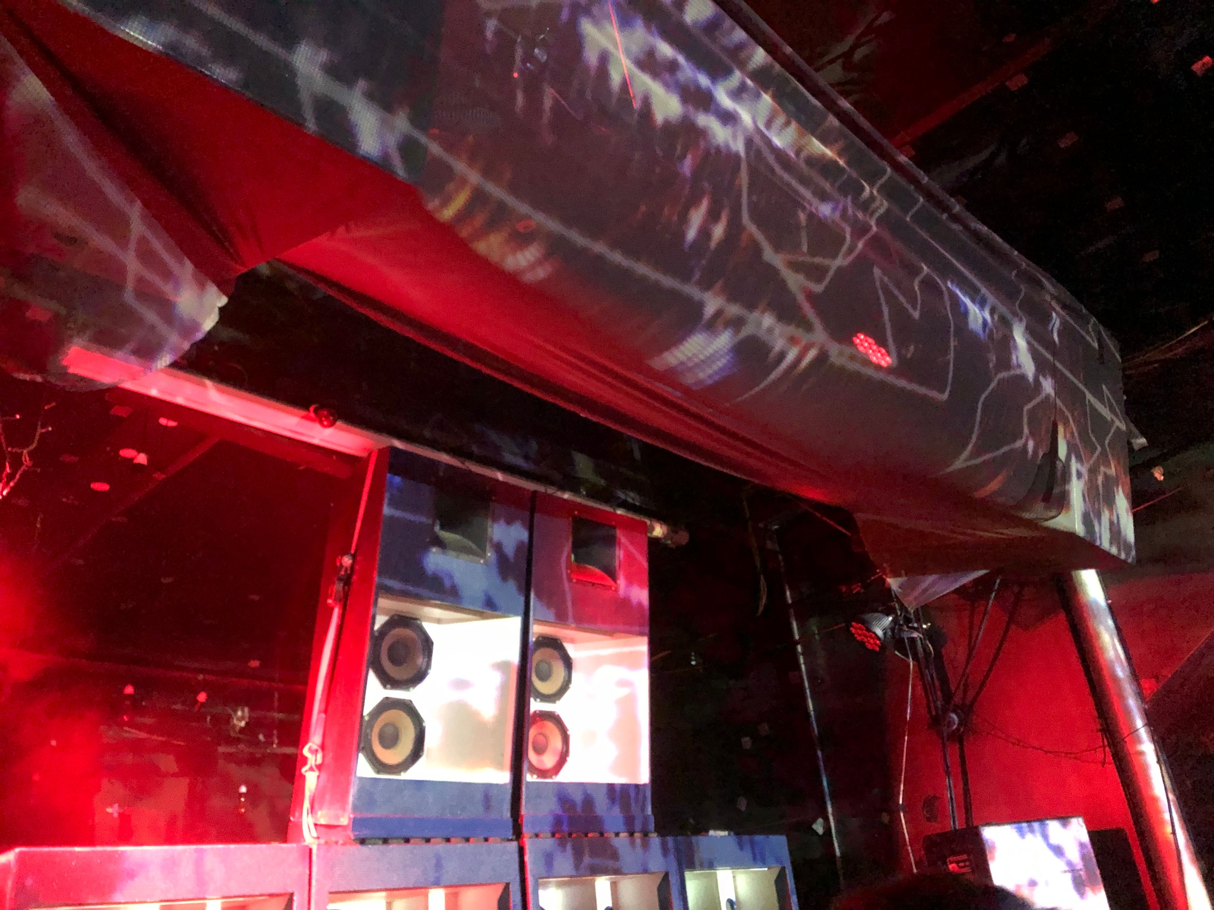 An image of a speaker stack in front of a stage (it looks like the Third Eye HiFi rig) with warm yellow lighting and visuals